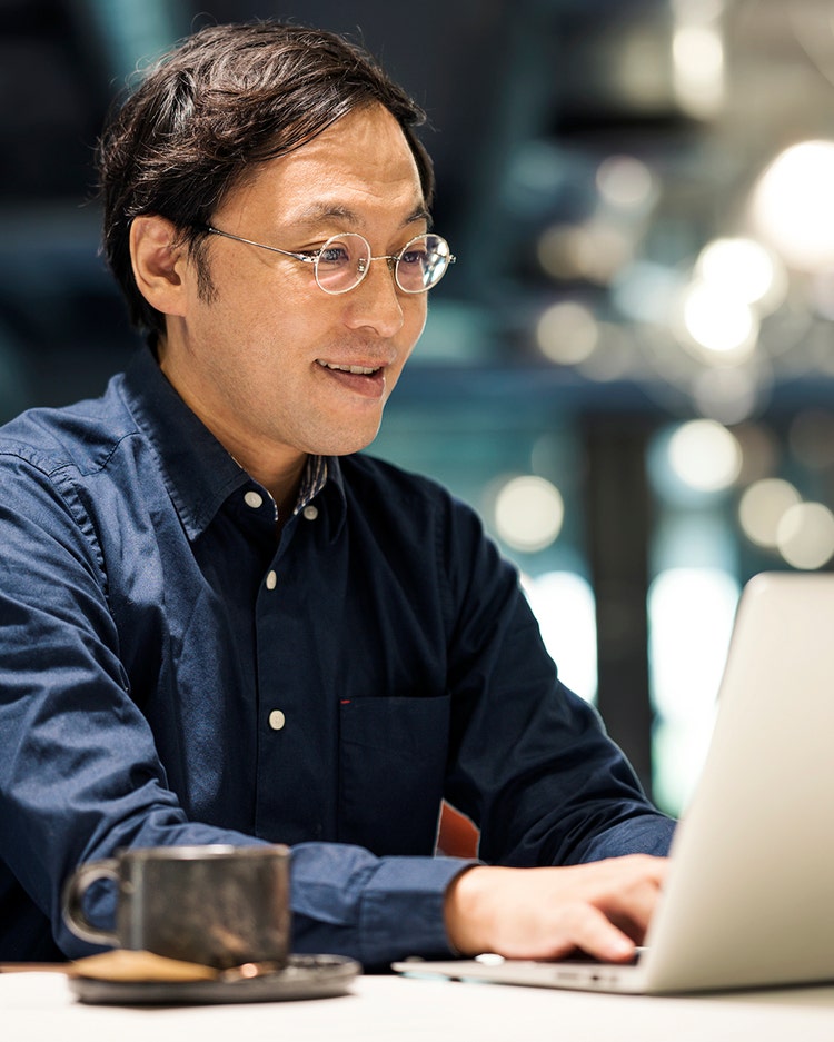 Technology Drives Business Growth. Japanese Businessman typing and replying email by a laptop to his customer in the office space.